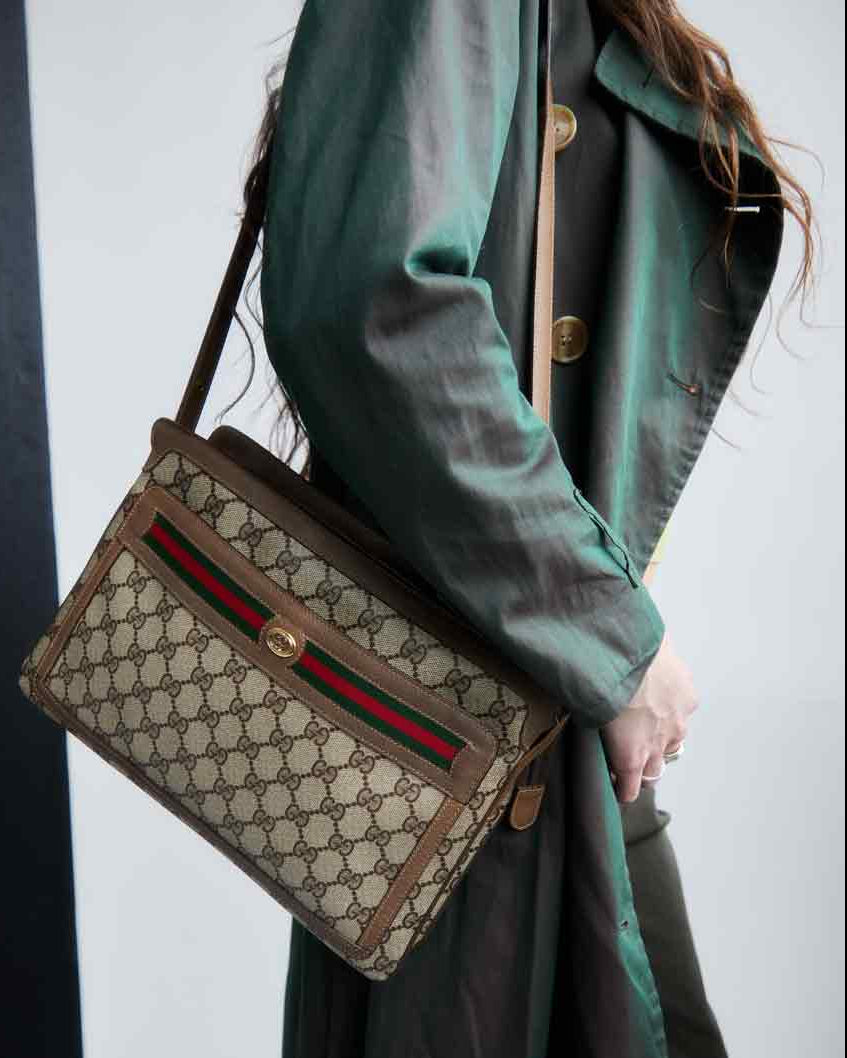 Person holding a Gucci handbag with a green coat